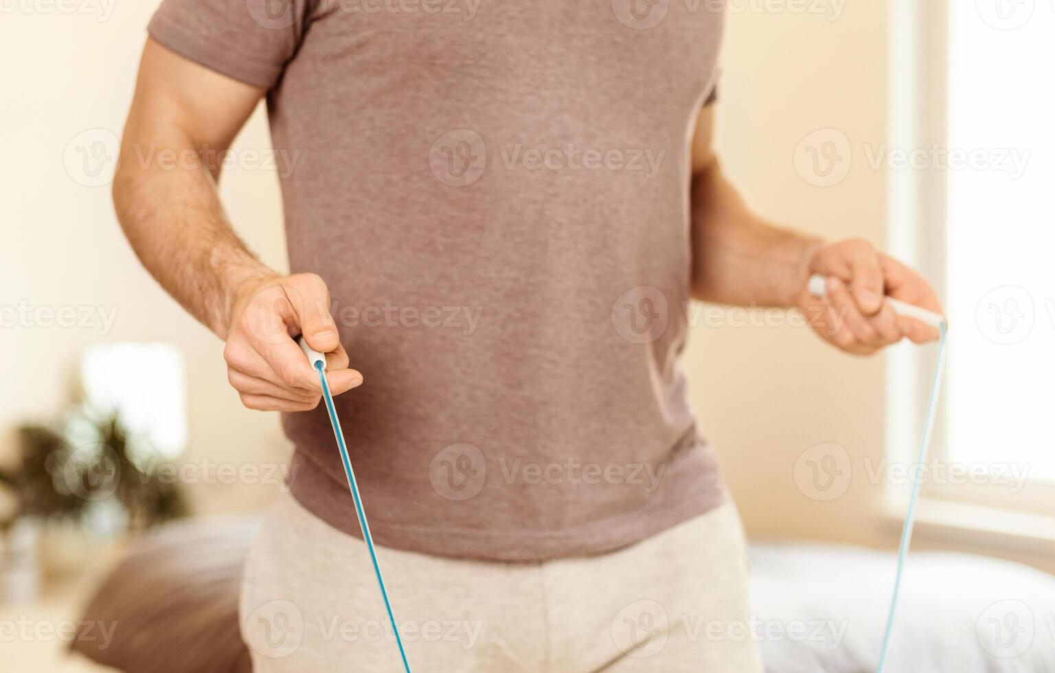 Unrecognizable Guy Holding Jump Rope Exercising Training At Home In The Morning. Physical Workout Routine With Jumping Rope, Sporty Lifestyle Concept. Cropped photo
