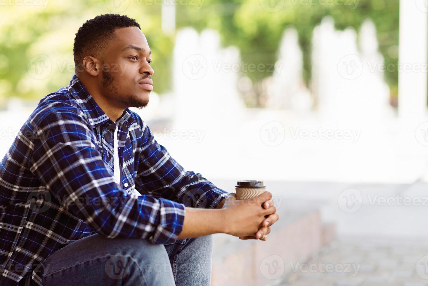 Side view of pensive african american person sitting in the park with coffee, looking aside, free space photo