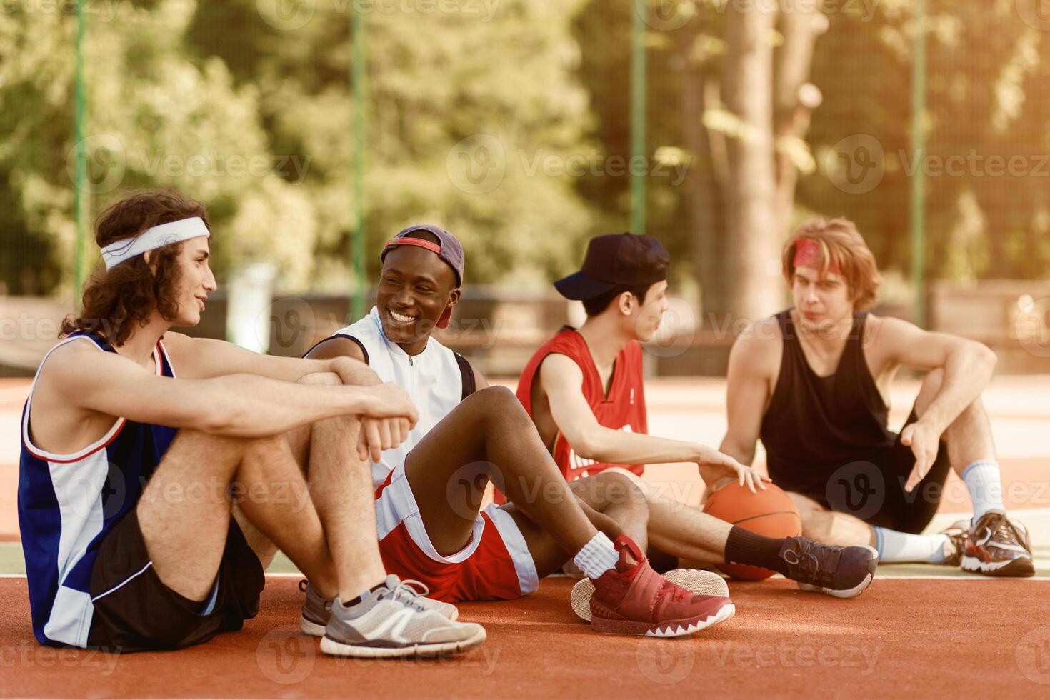 Multiracial basketball team taking break after their game at outdoor arena, empty space photo