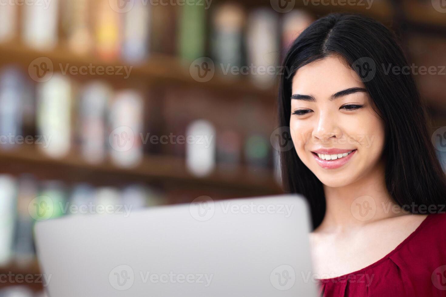 Online Career. Positive Asian Girl Freelancer Working On Laptop In Cafe, Looking At Computer Screen And Smiling, Closeup Shot With Free Space photo
