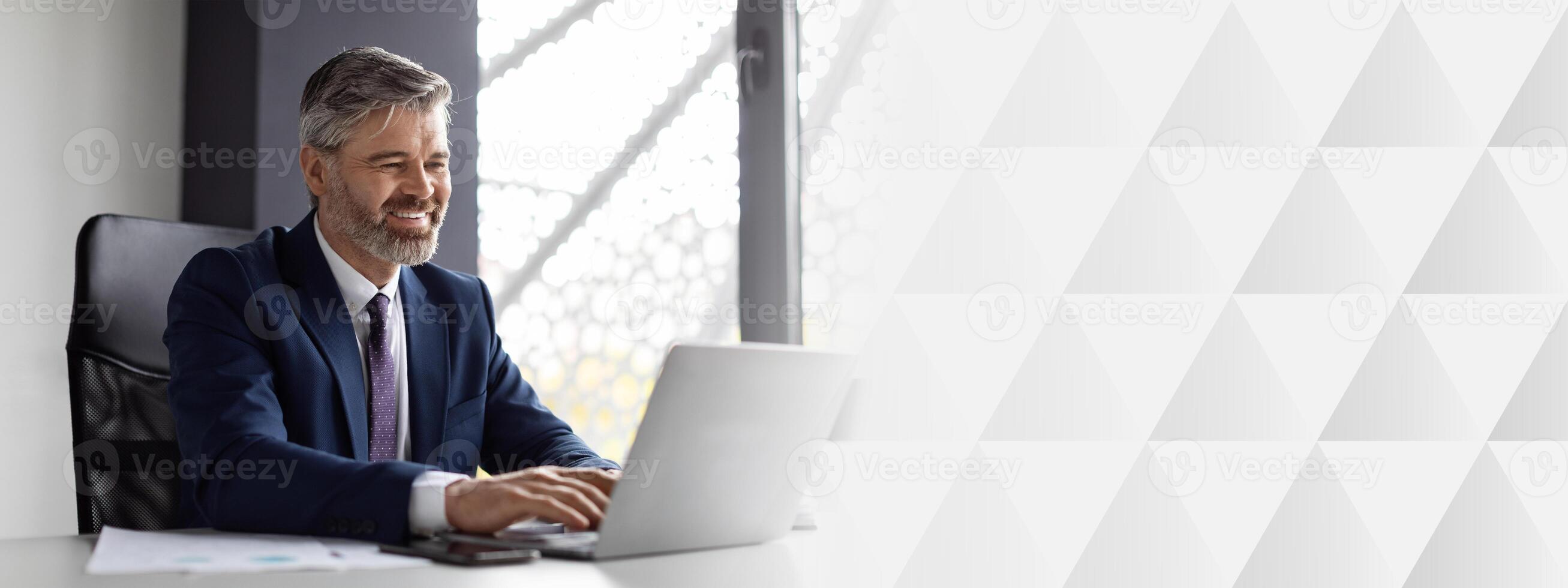 Smiling Middle Aged Businessman Working With Laptop Computer In Office, Handsome Man Entrepreneur In Suit Sitting At Desk And Typing On Keyboard, Enjoying Corporate Communication, copy space photo