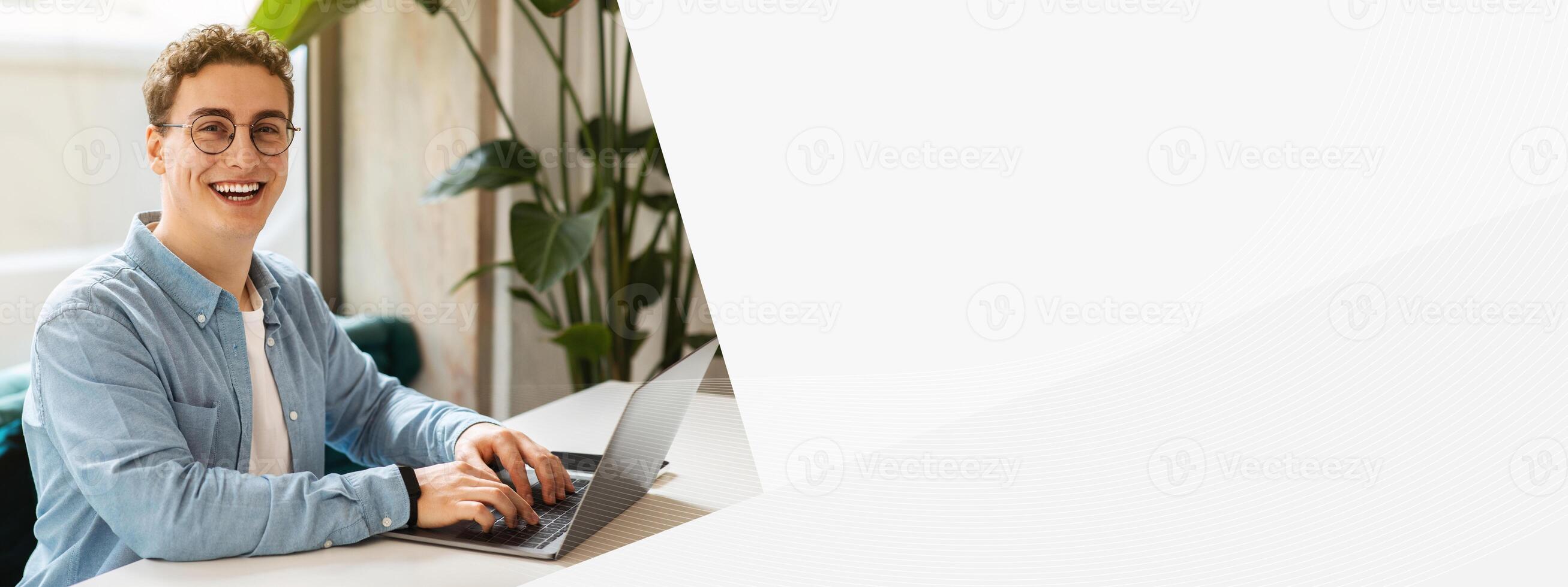 Cheerful young european man student in glasses, typing on laptop, work, study or online communication in cafe with phone. Online meeting, modern lifestyle remotely, digital nomad photo