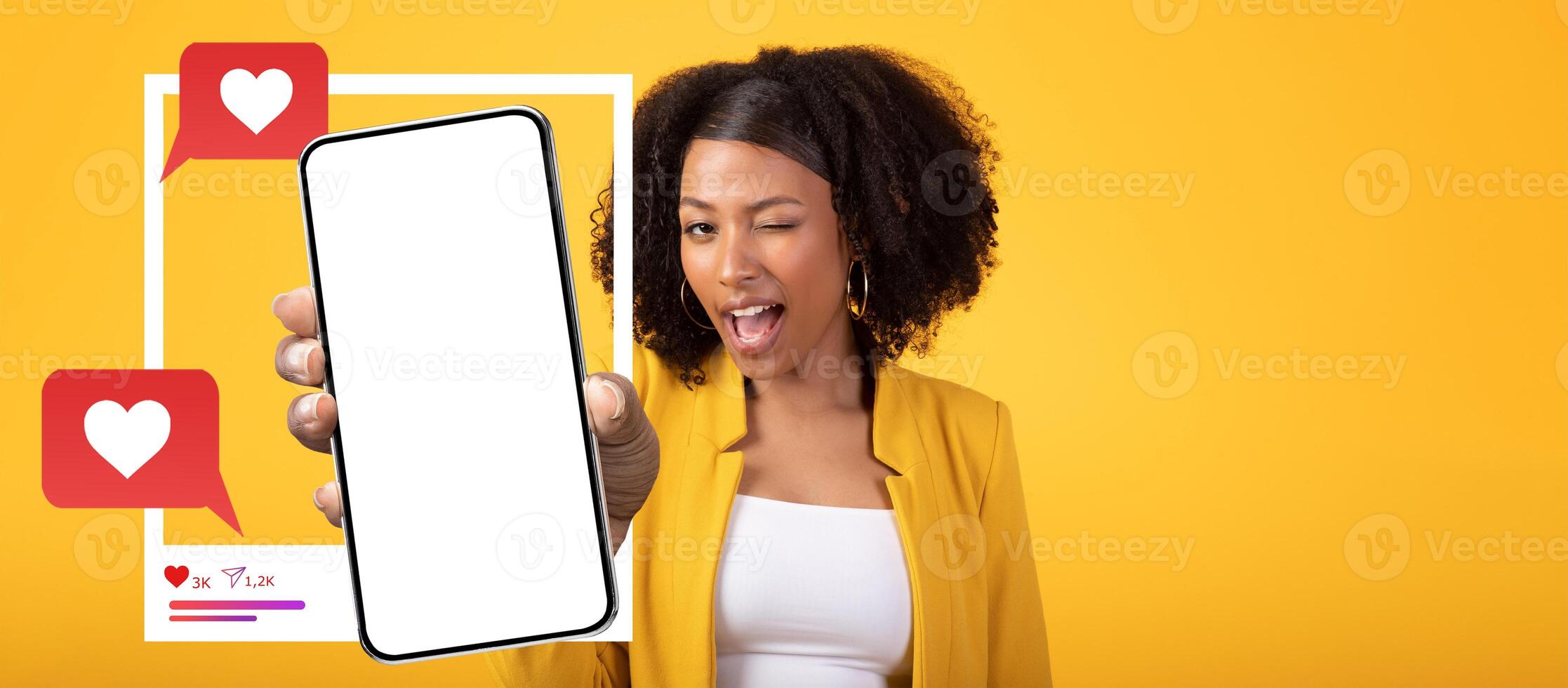 A confident influencer with curly hair holds a smartphone displaying a blank screen. Set against a bright yellow background, heart icons and chat bubbles emphasize social media engagement. photo