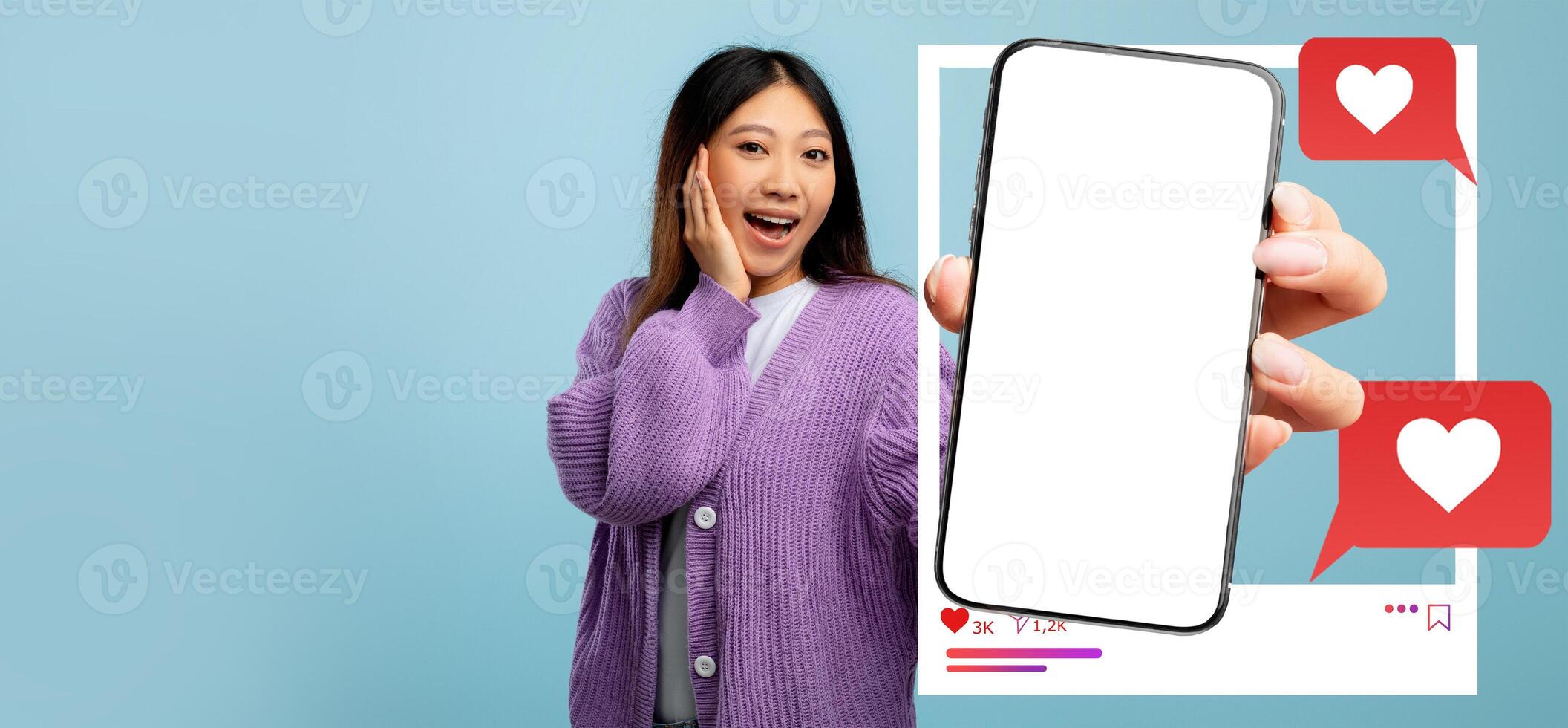 A young influencer holds a smartphone displaying a blank screen with heart icons and likes. She is excitedly engaging with her online audience, promoting social media interaction. photo
