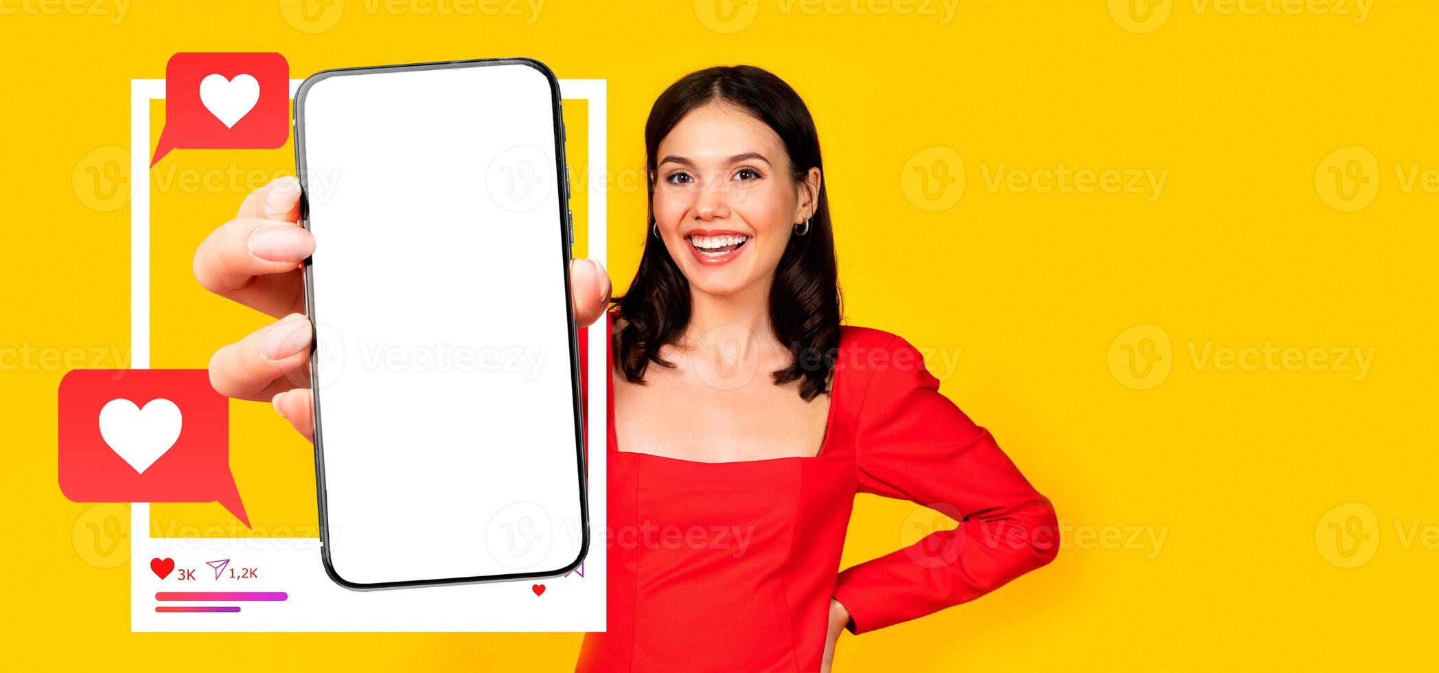 A cheerful influencer holds a smartphone displaying a blank screen, perfect for social media interactions. Bright yellow background highlights her engaging personality and online presence. photo