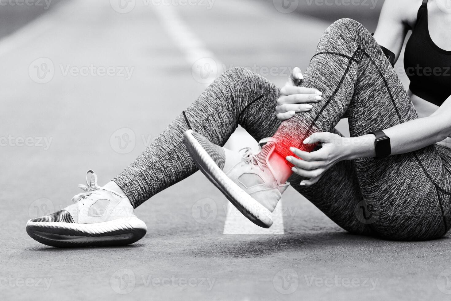Sad Asian Girl Having Ankle Pain After Jogging In Park, Massaging Red Sore Spot, Sitting On Path, BW Style With Free Space photo