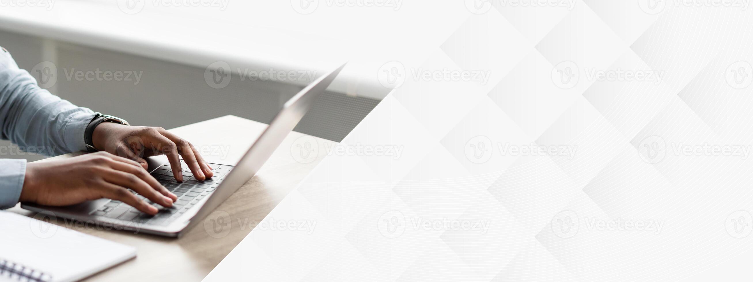 Black Businessman Working On Laptop Wearing Earbuds Sitting At Workplace In Modern Office. Successful Own Business And Entrepreneurship Career Concept. Side View photo