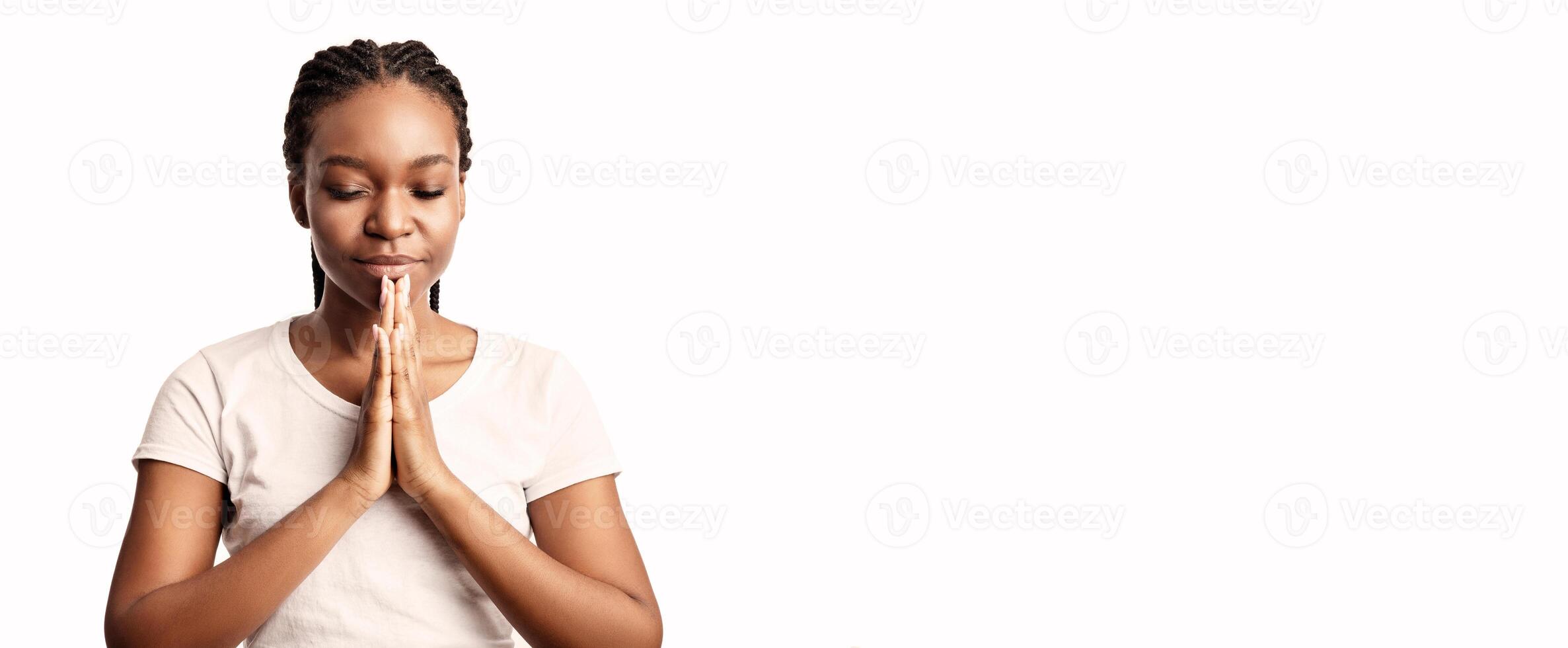 A young woman engages in a moment of reflection, practicing mindfulness with her hands in a prayer position. She appears centered and serene, suggesting inner peace and focus. photo