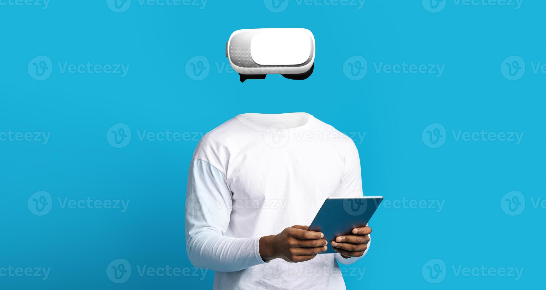 A person is using a virtual reality headset while holding a tablet. The setting features a vibrant blue background, highlighting the technology and modern gadgets utilized in the experience. photo