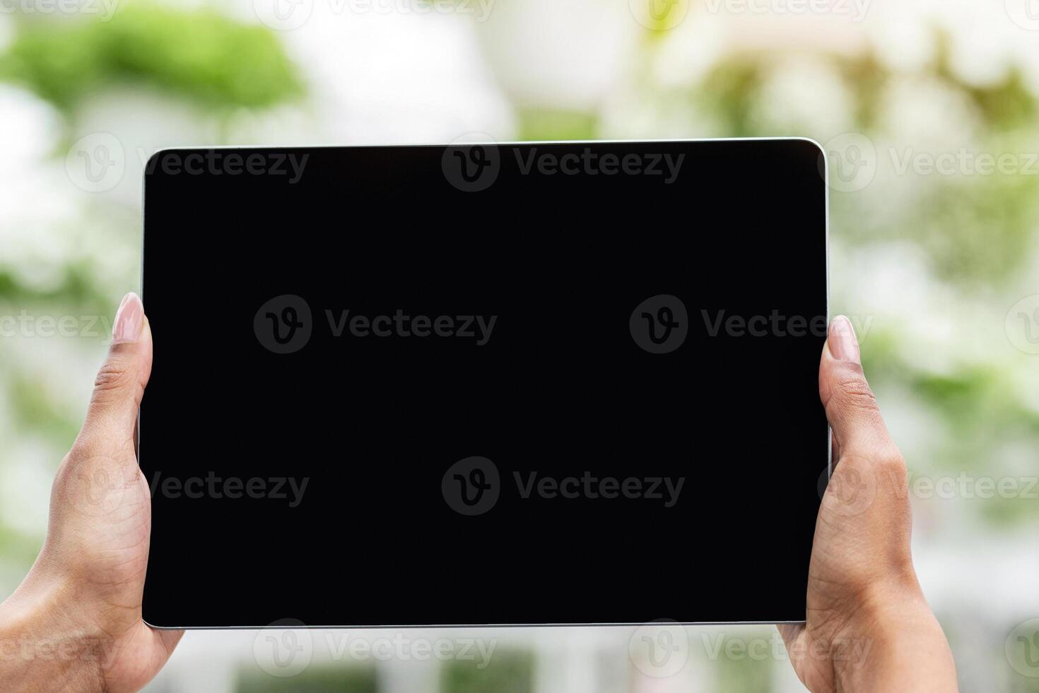Industrial cultivation of potted plants with modern technology. Hands of african american girl with smartwatch holding tablet with empty screen on greenhouse background, pov, close up photo