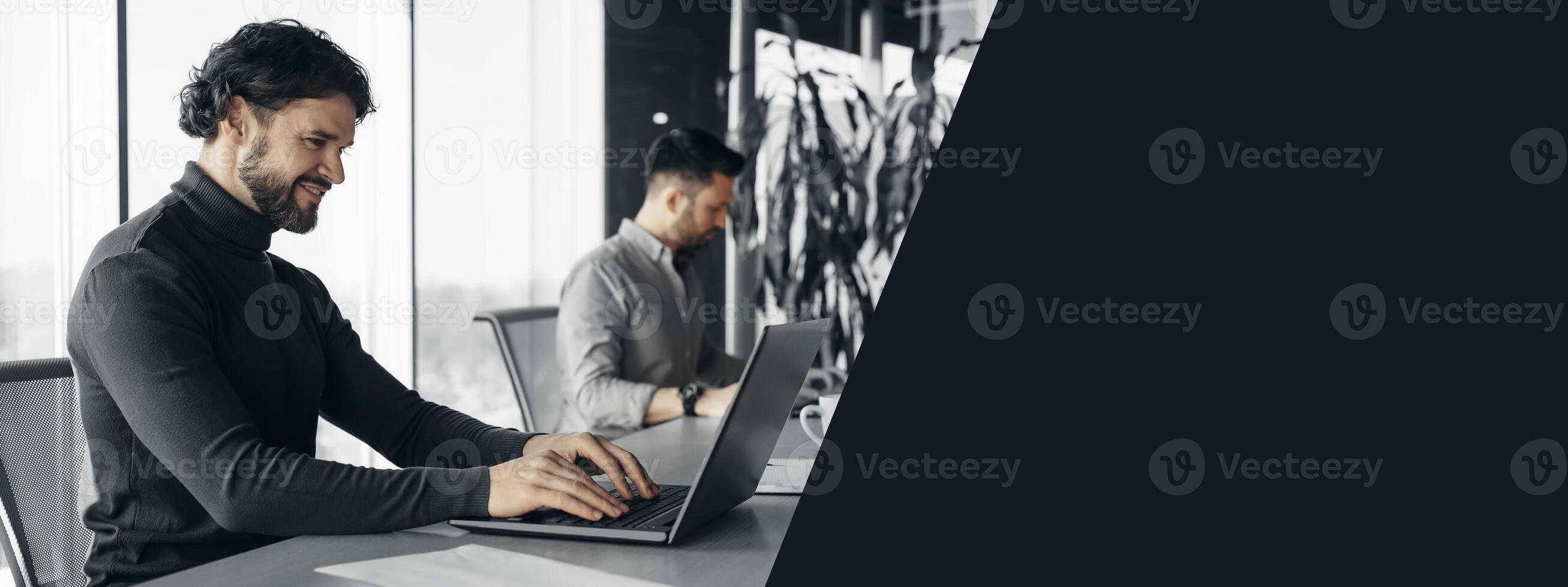 Happy company employee using laptop, working next to man colleague at open space office. Professional occupation, business cooperation, teamwork and collaboration concept photo