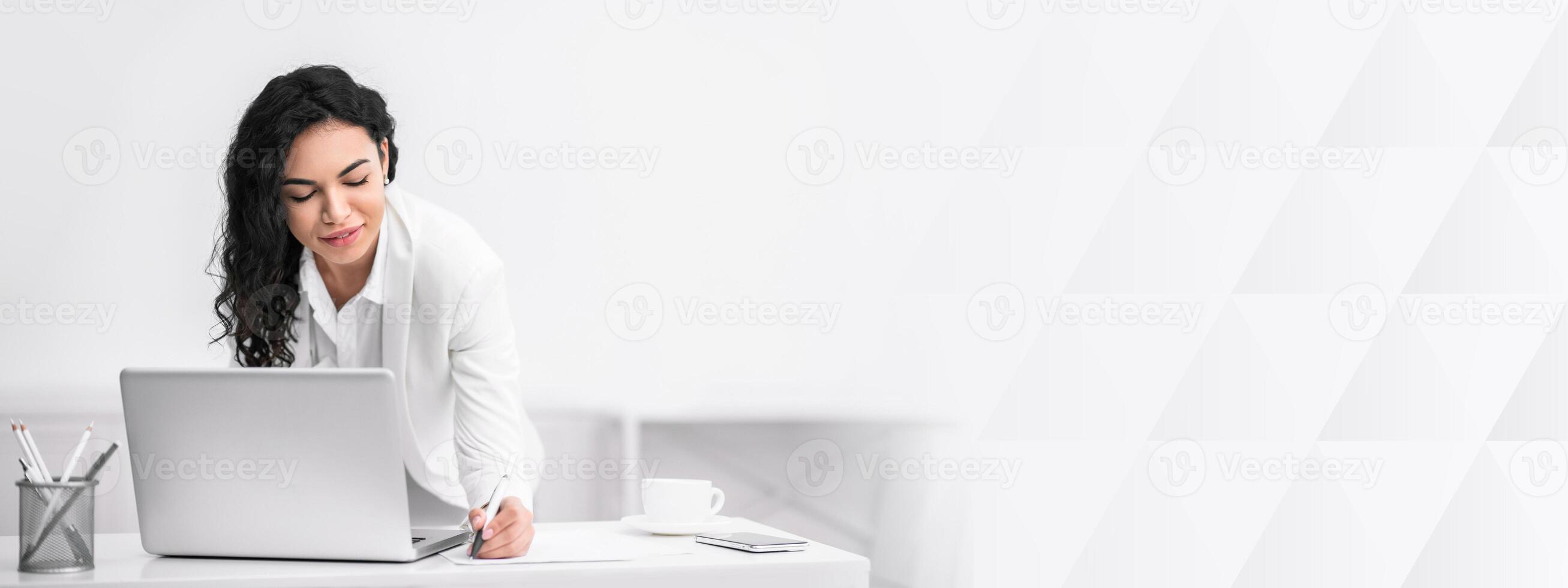 Business People Concept. Beautiful mexican freelancer lady writing notes using laptop computer working online, copy space photo