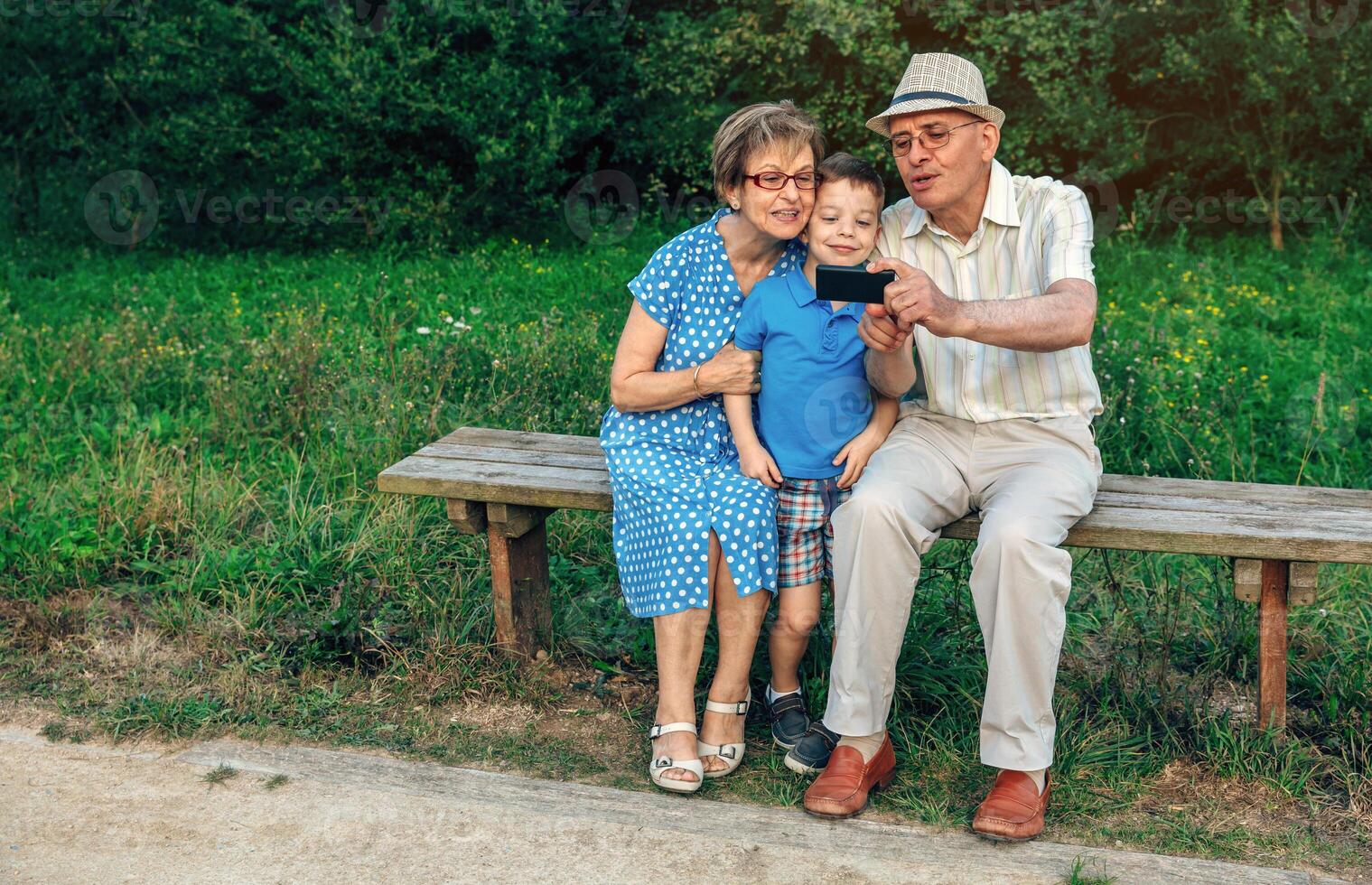 Grandparents and grandson taking selfie sitting on a bench photo