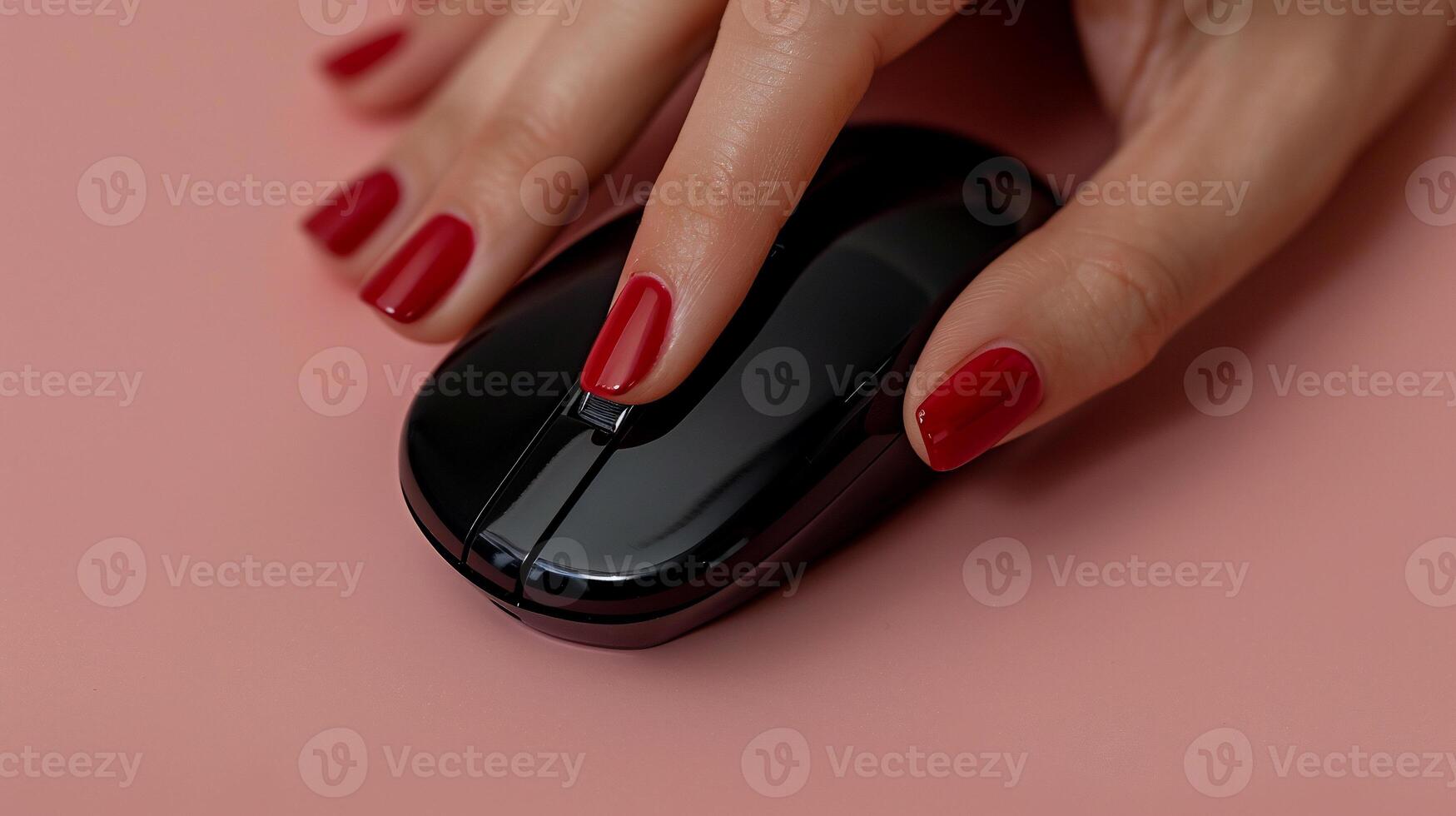 Woman's hand using a black computer mouse with red nails on a pink surface photo