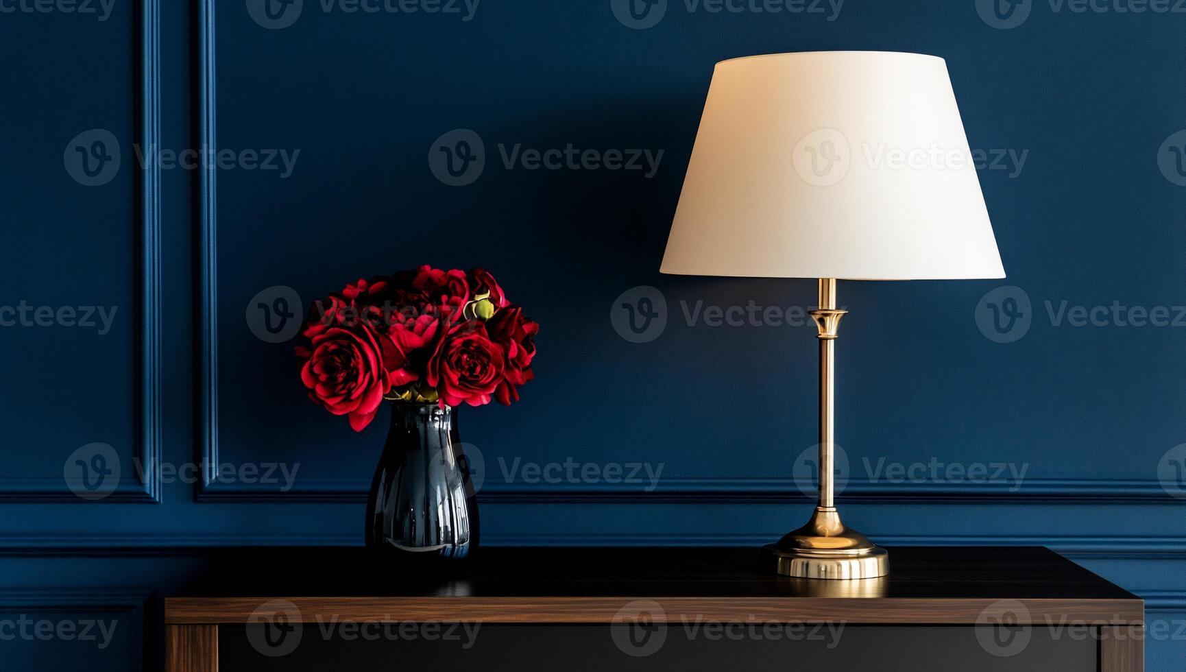 Dark navy wall, red roses in vase, gold lamp photo