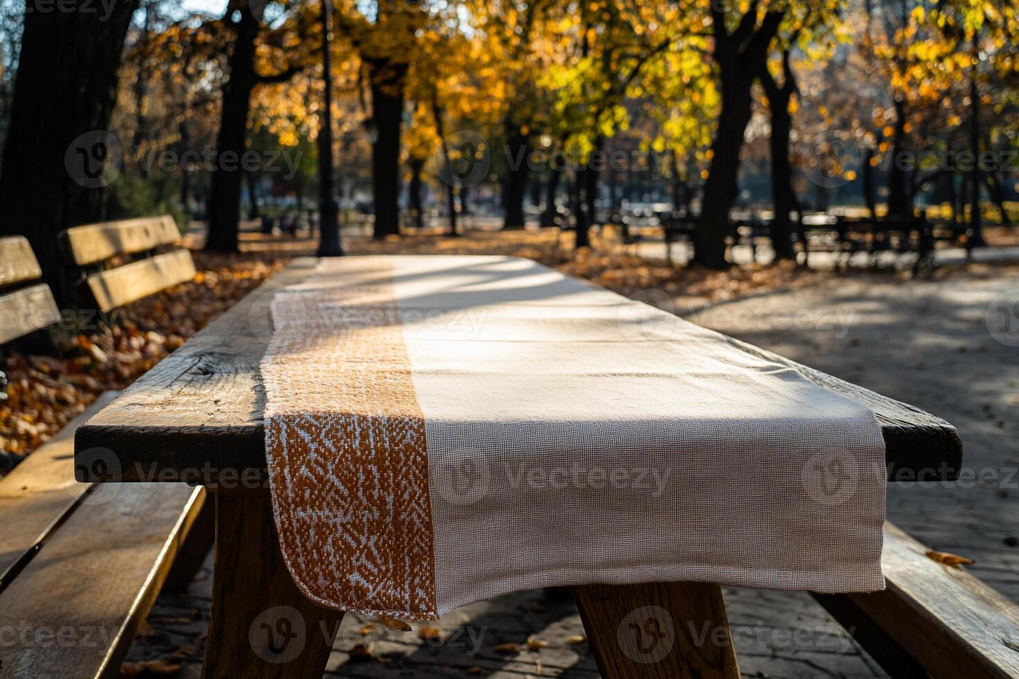 Empty wooden picnic table with cream tablecloth in autumn park photo