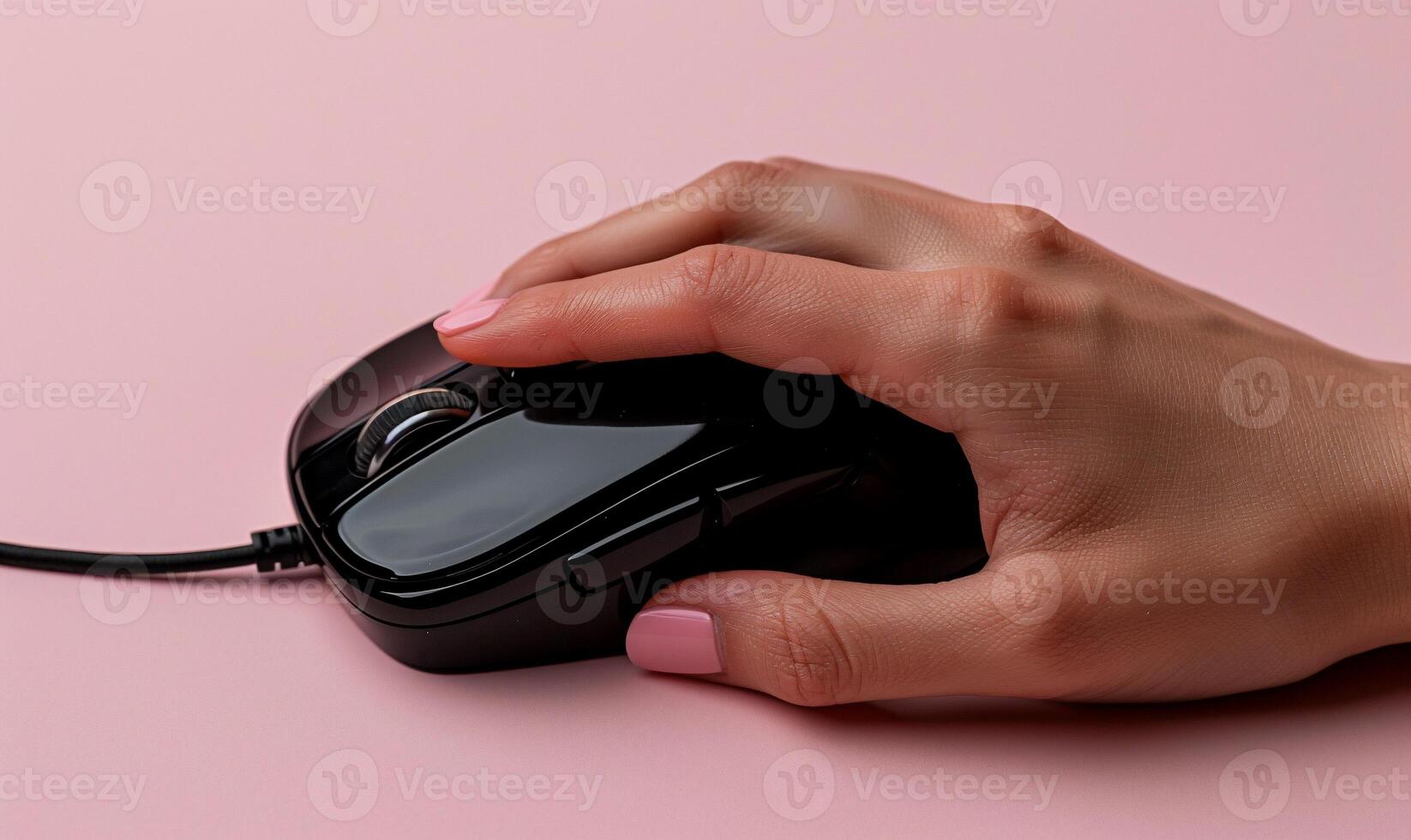 Hand holding black computer mouse on pink background photo