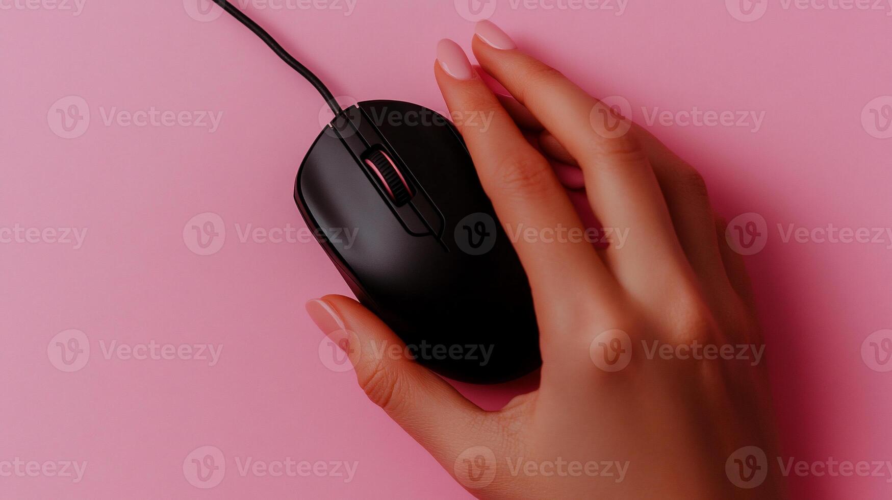 Hand using a black computer mouse on a pink surface photo