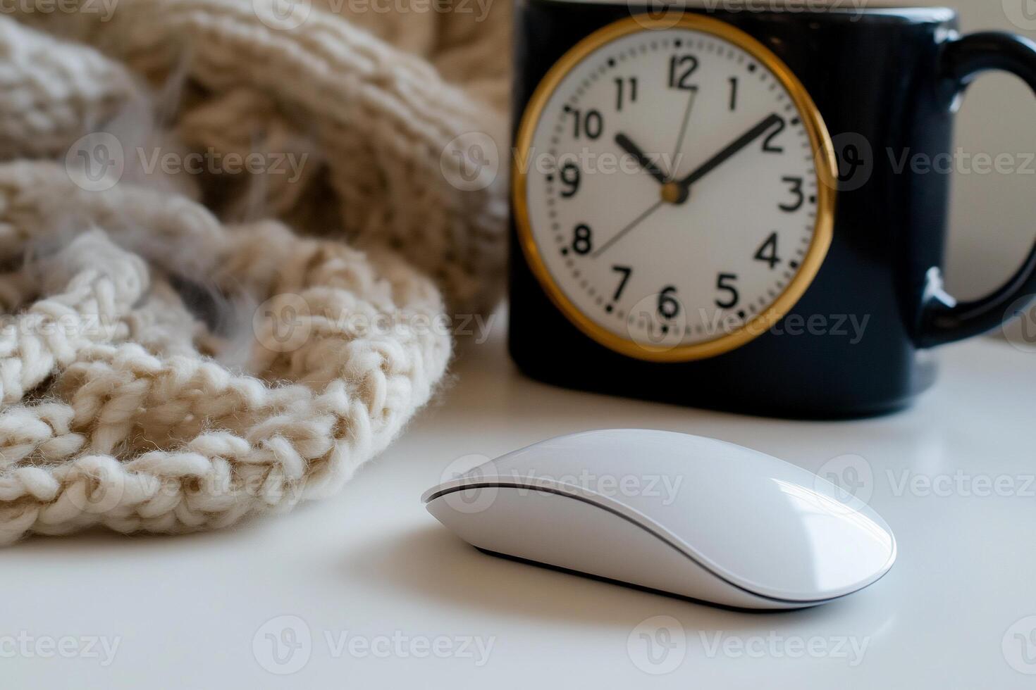 Cozy workspace with a warm knit blanket, a clock, and a computer mouse on a white surface photo