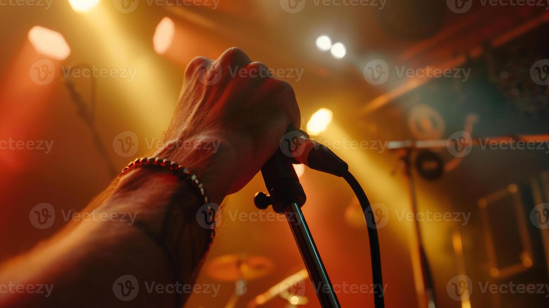 Close-up of a hand holding a microphone on stage, vibrant lighting, music performance photo