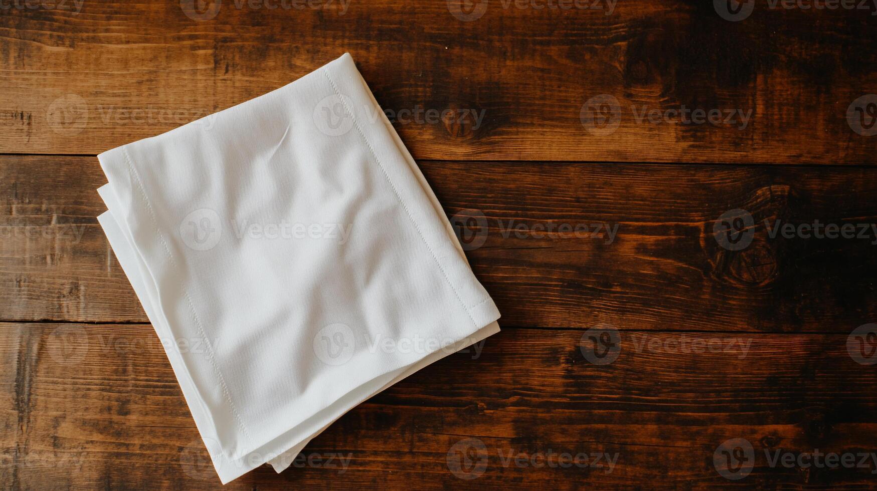 Folded white cloth napkin on a dark wooden table photo