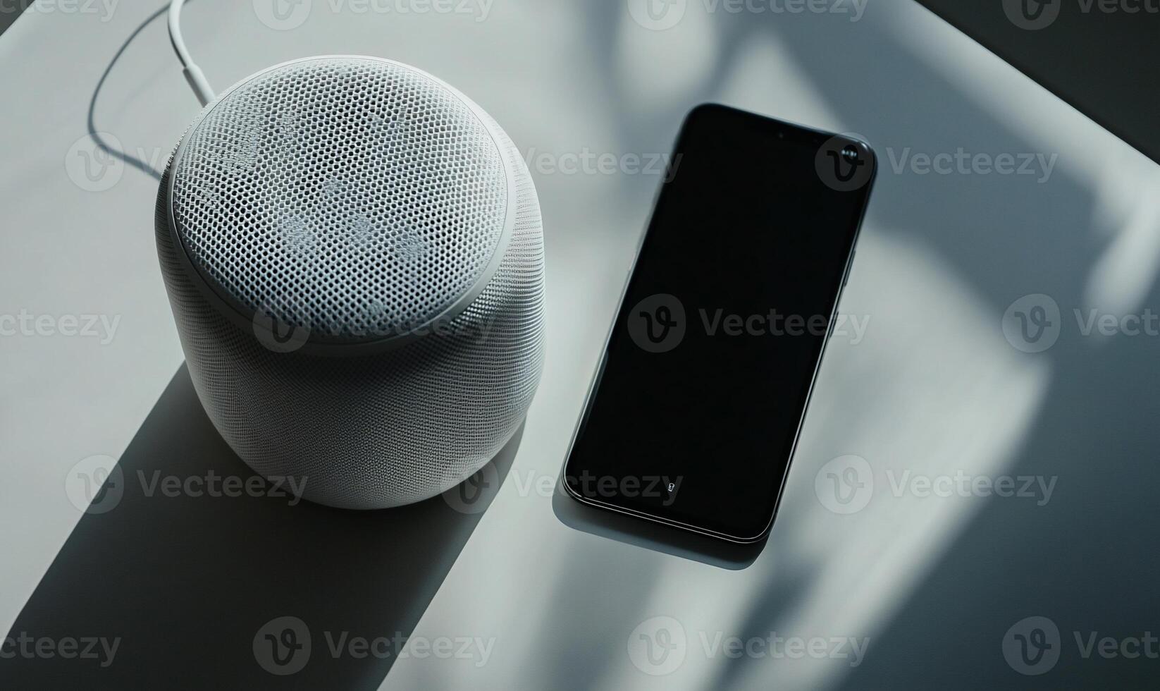 White smart speaker and phone on a light surface photo