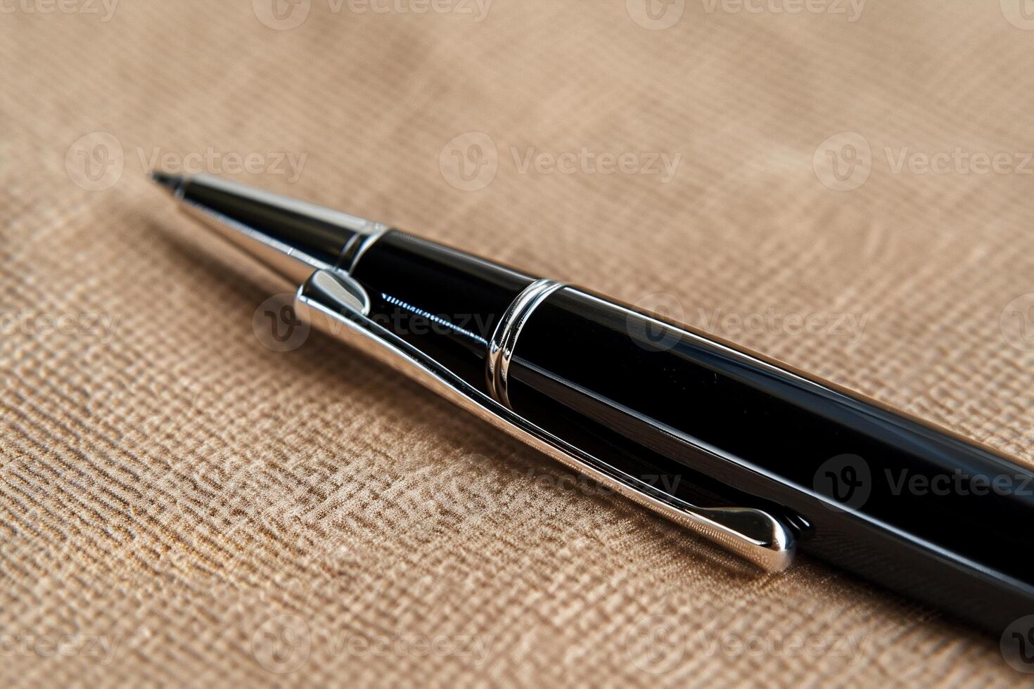 Close-up of a black pen on a beige fabric. The pen's tip and body are clearly visible, showcasing its metallic accents photo