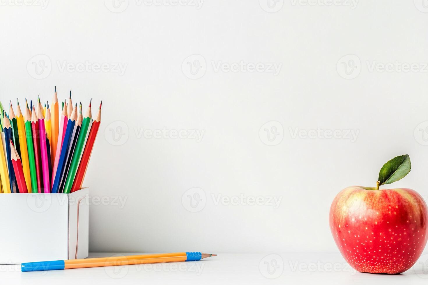 An apple and pencils on a white table photo