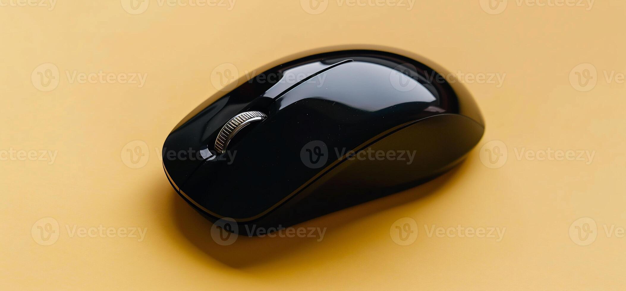 Sleek black wireless computer mouse on a mustard yellow background photo