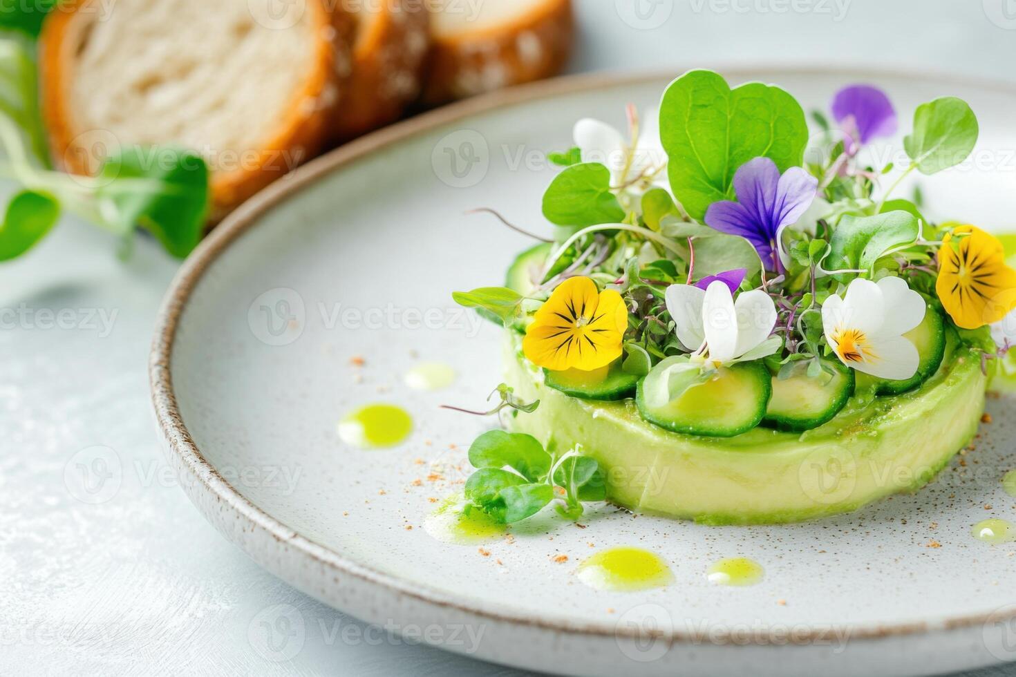 A deconstructed avocado salad is served on a ceramic plate, garnished with microgreens and edible flowers, accompanied by artisan bread photo