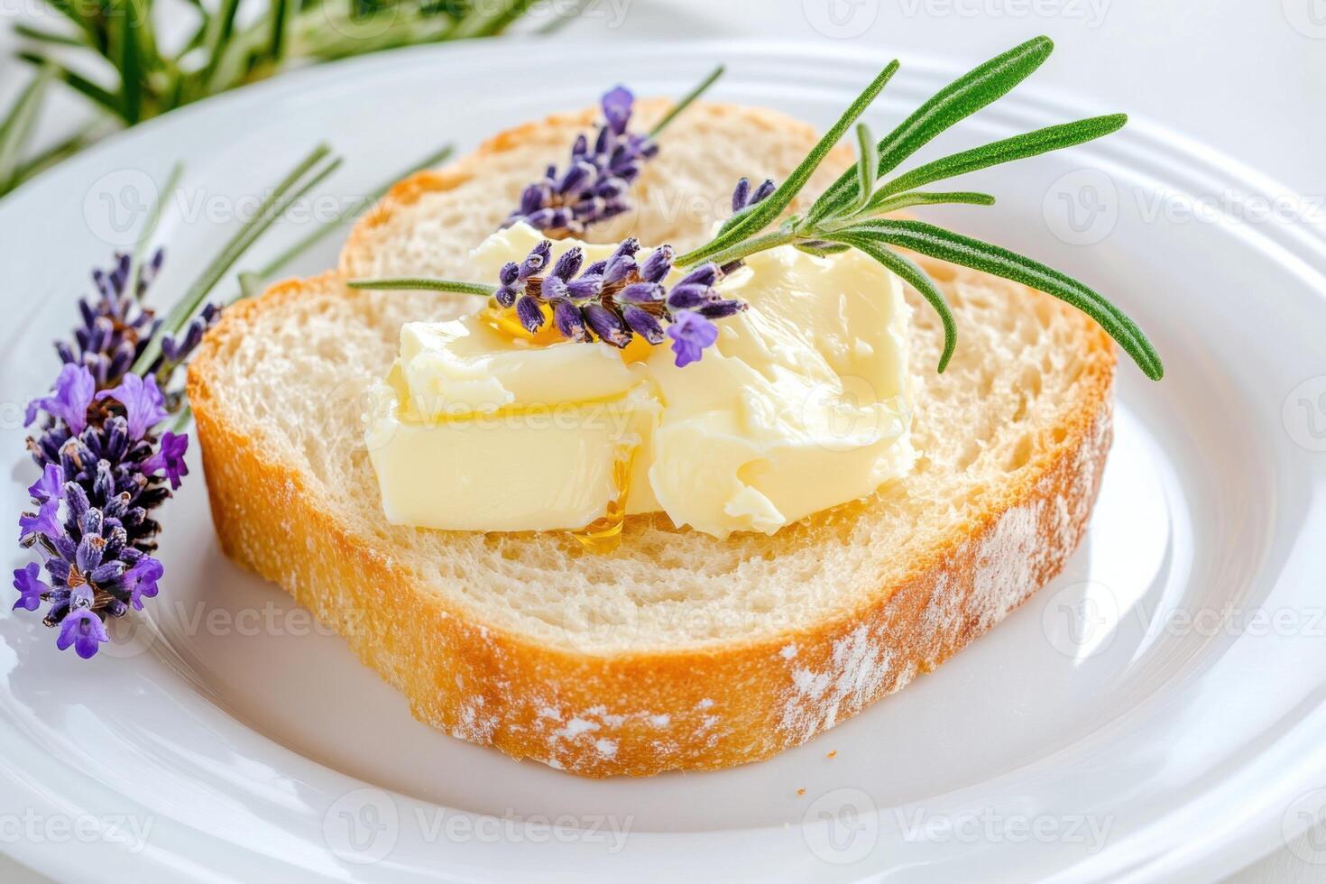 Slice of freshly baked bread with melting butter, drizzled honey and lavender sprigs placed on a white plate photo