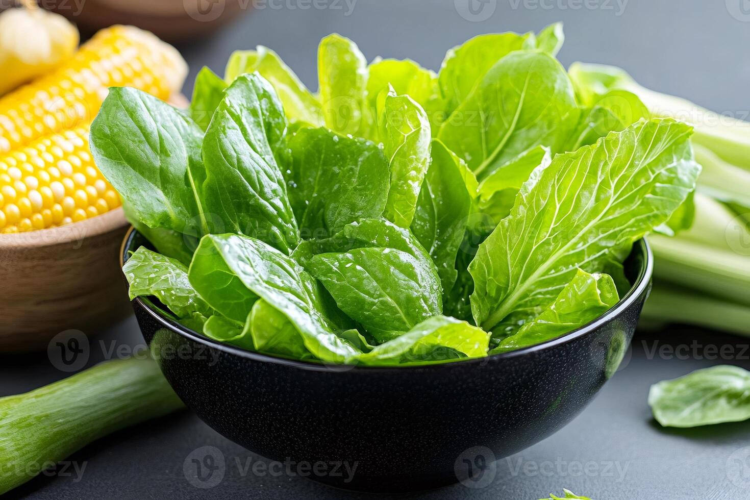 Fresh green baby spinach leaves in a black bowl with corn and celery on a dark background photo