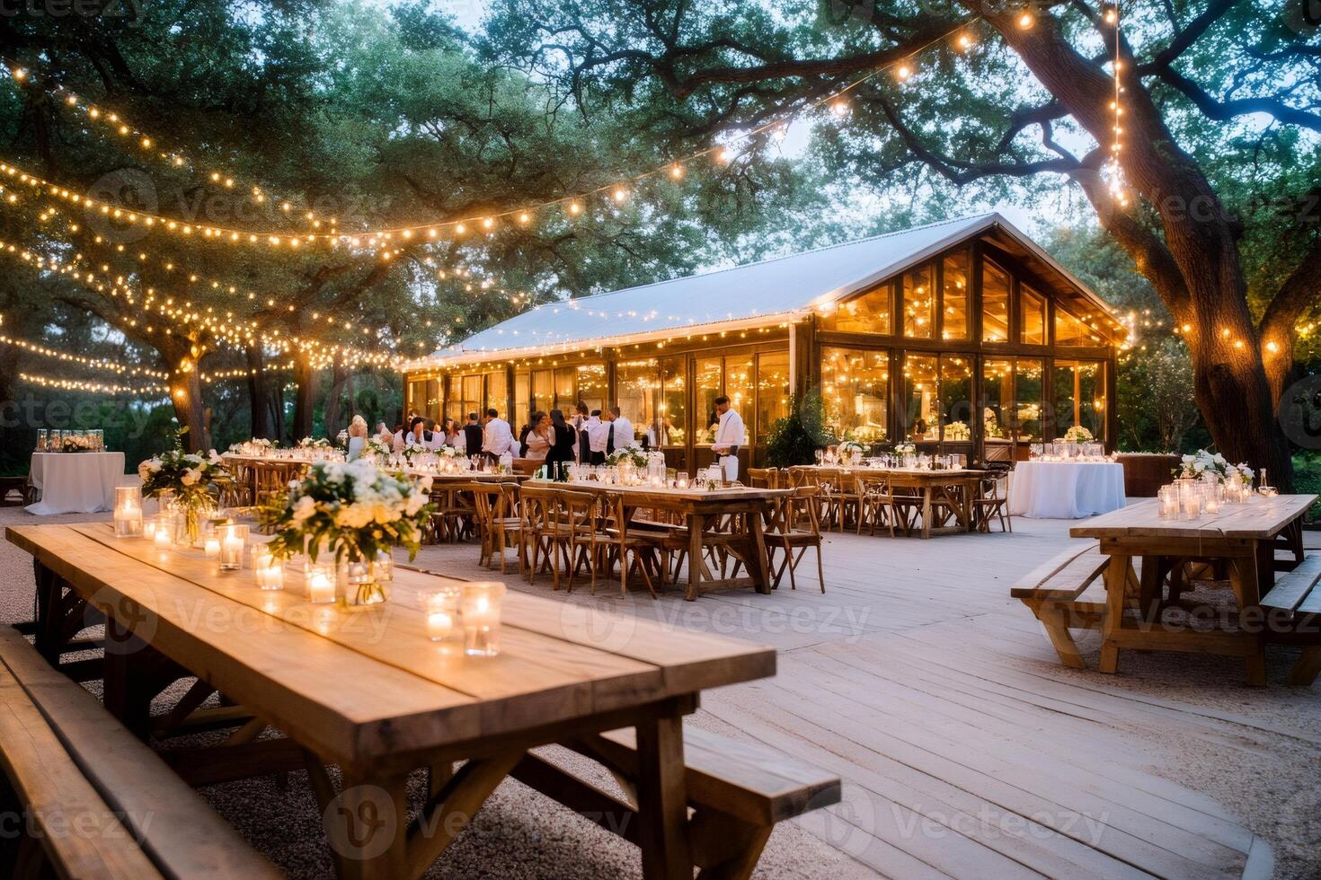 Outdoor wedding reception taking place at night with string lights illuminating wooden tables photo