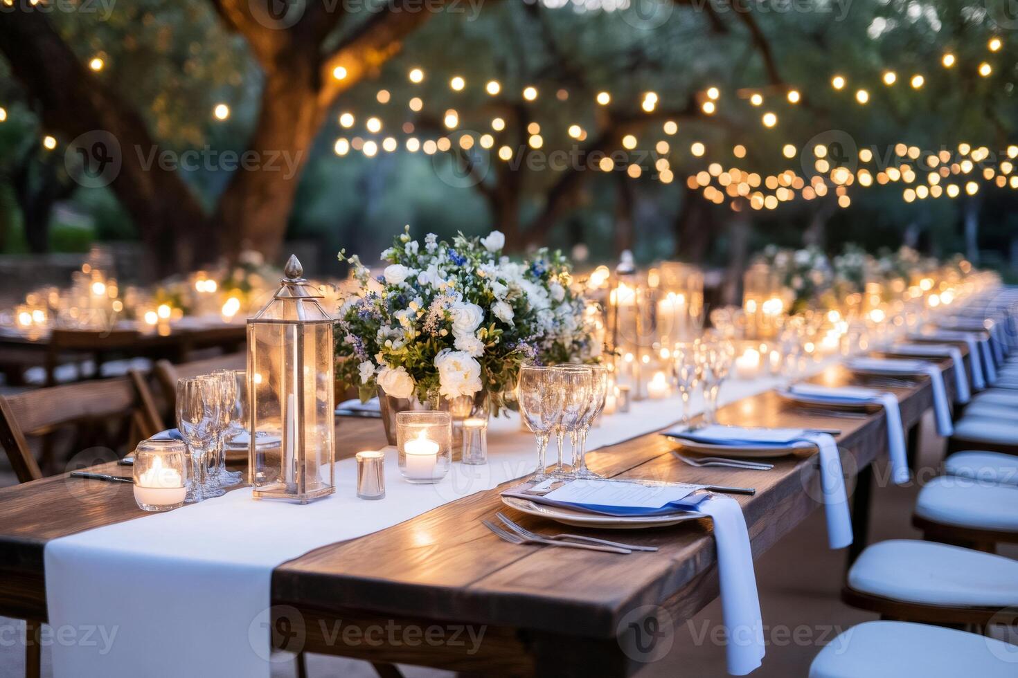 Wedding reception table setting outdoors with hanging lights and candles creating a romantic atmosphere photo