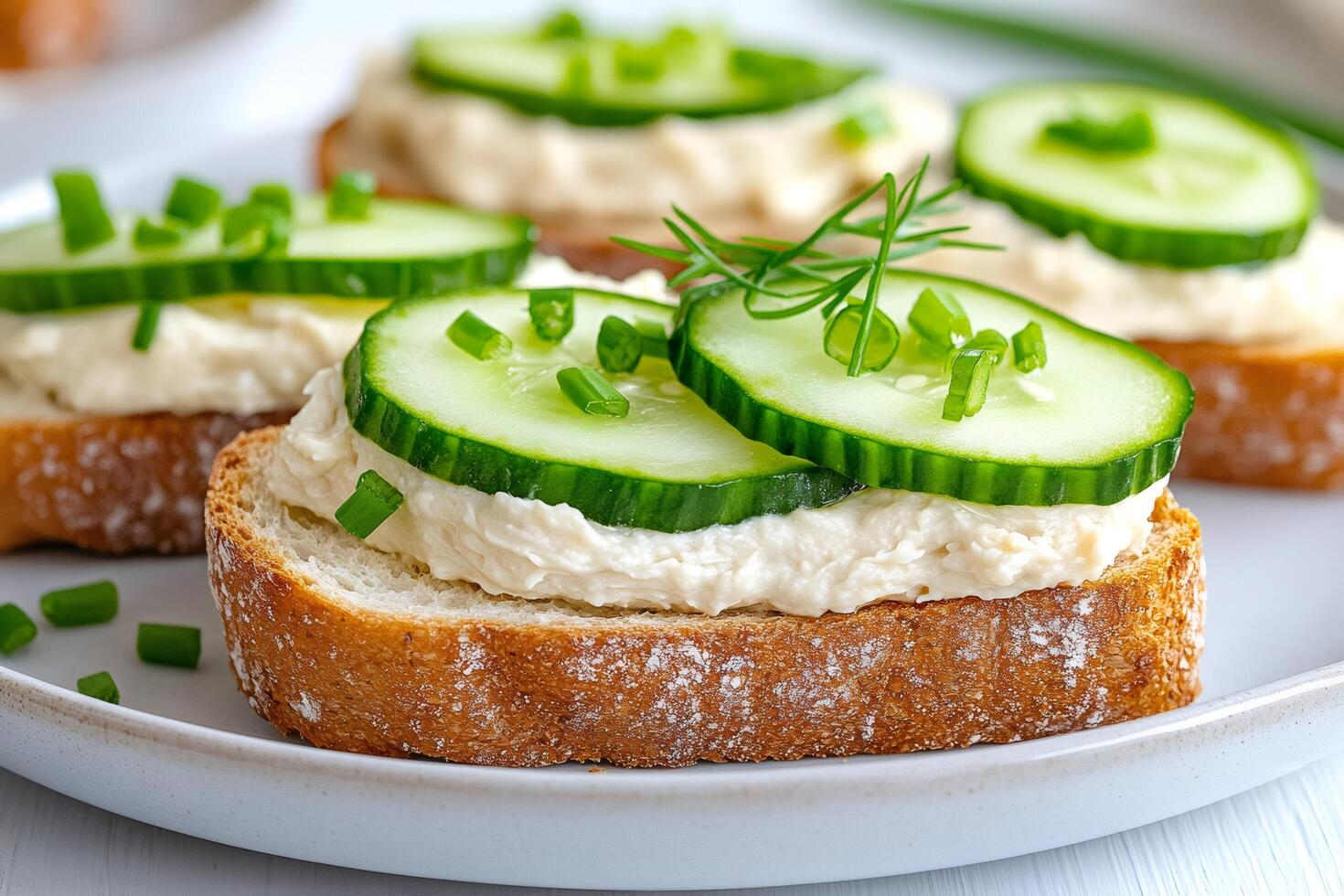 Chef preparing bread with cream cheese, cucumber and chives on toasted slices of baguette photo