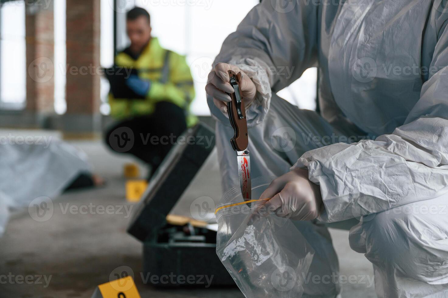 Putting,, the knife into bag. Detectives are collecting evidence in a crime scene near dead body photo
