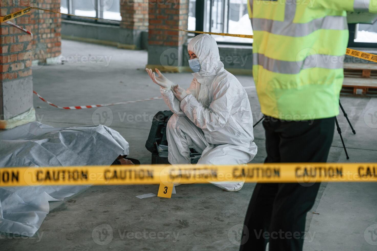 Woman is putting on the gloves. Detectives are collecting evidence in a crime scene near dead body photo