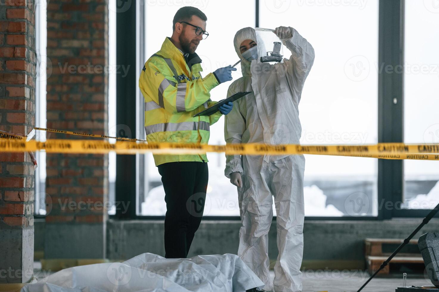 At daytime.. Detectives ,are collecting evidence, in a crime scene near dead body photo