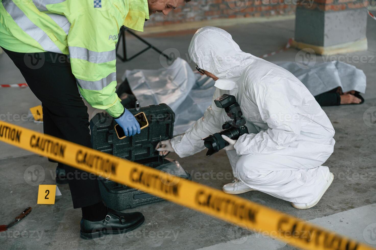 Caution police tape. Detectives are collecting evidence in a crime scene near dead body photo