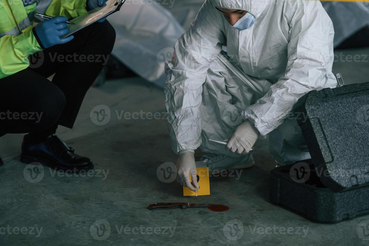 Detectives ,are collecting evidence, in a crime scene near dead body. Forensic specialists are making expertise photo