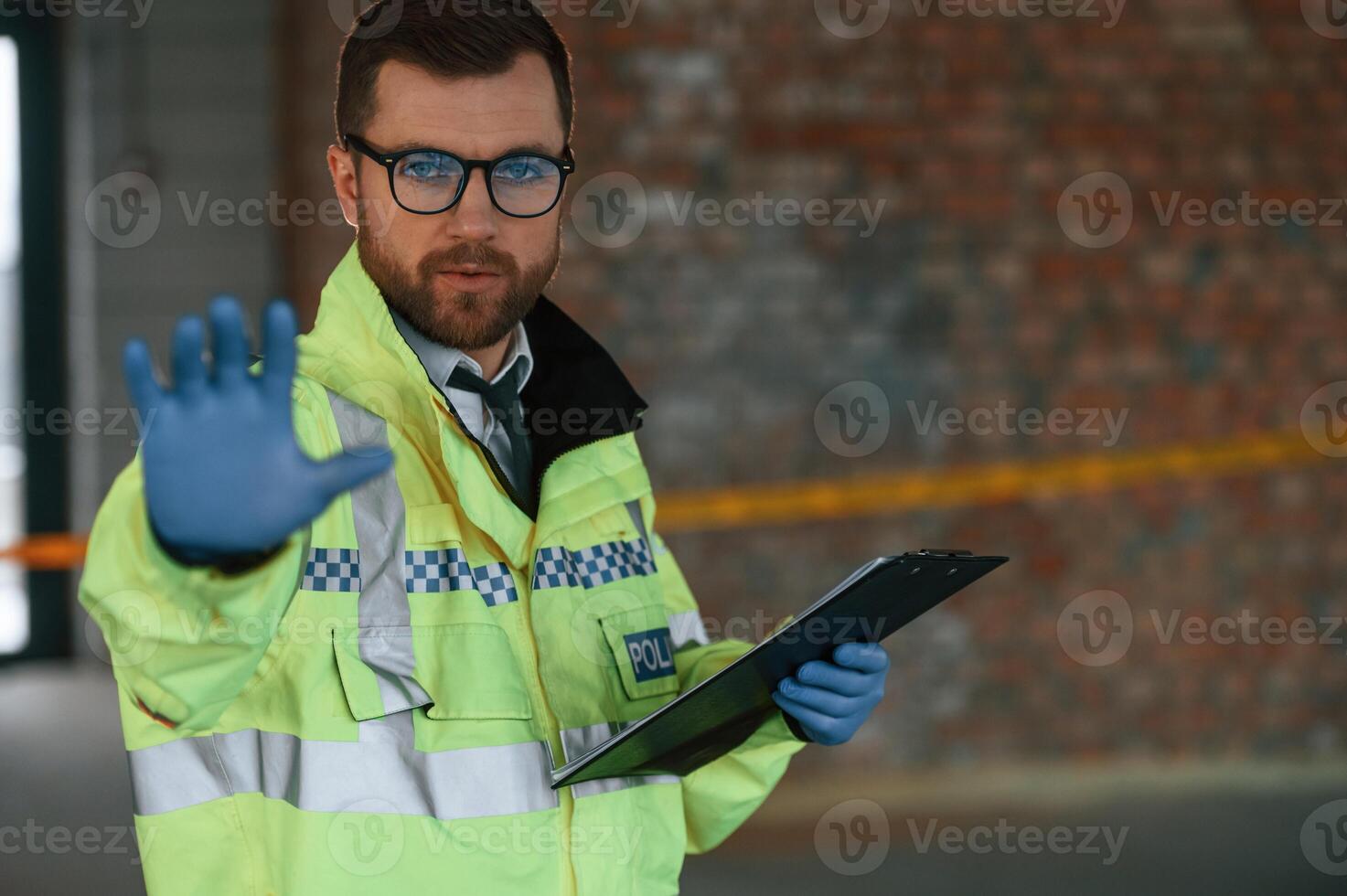 No, trespassing, stop gesture by a hand. Male detective is collecting evidence in a crime scene on the construction site photo