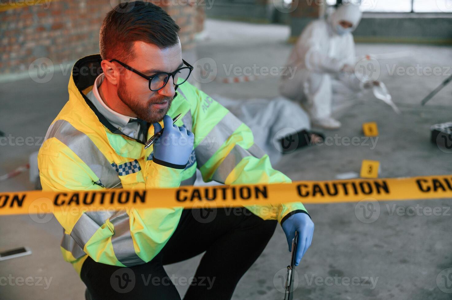 Sitting ,near, caution police tape. Detectives are collecting evidence in a crime scene with dead body photo