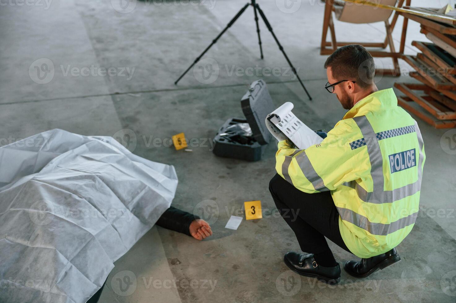Notepad with information.. Male detective is collecting evidence in a crime scene near dead body on the construction site photo