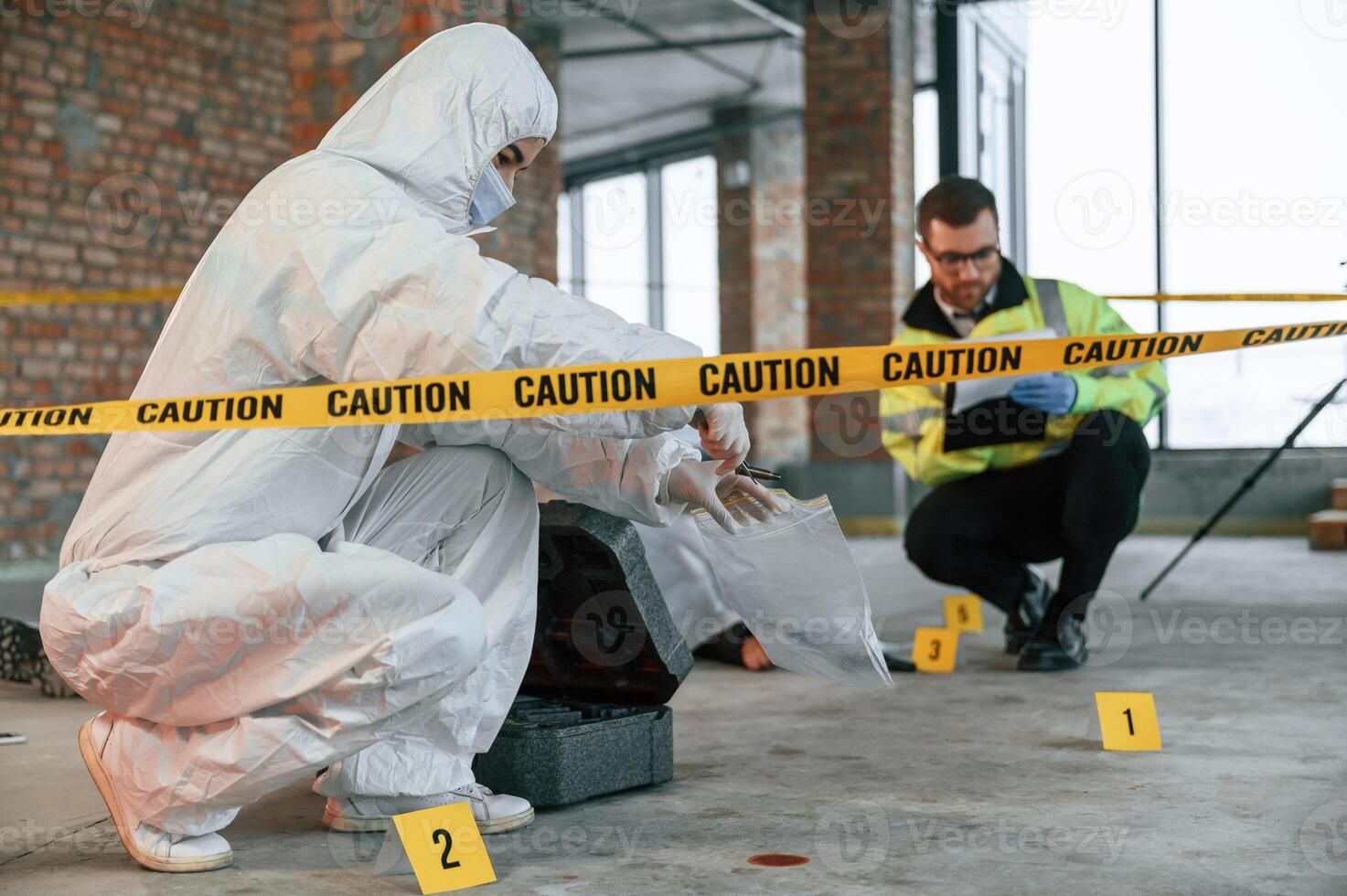 Woman ,holds the sleeve from the cartridge and puts it in the bag. Detectives are collecting evidence in a crime scene near dead body photo
