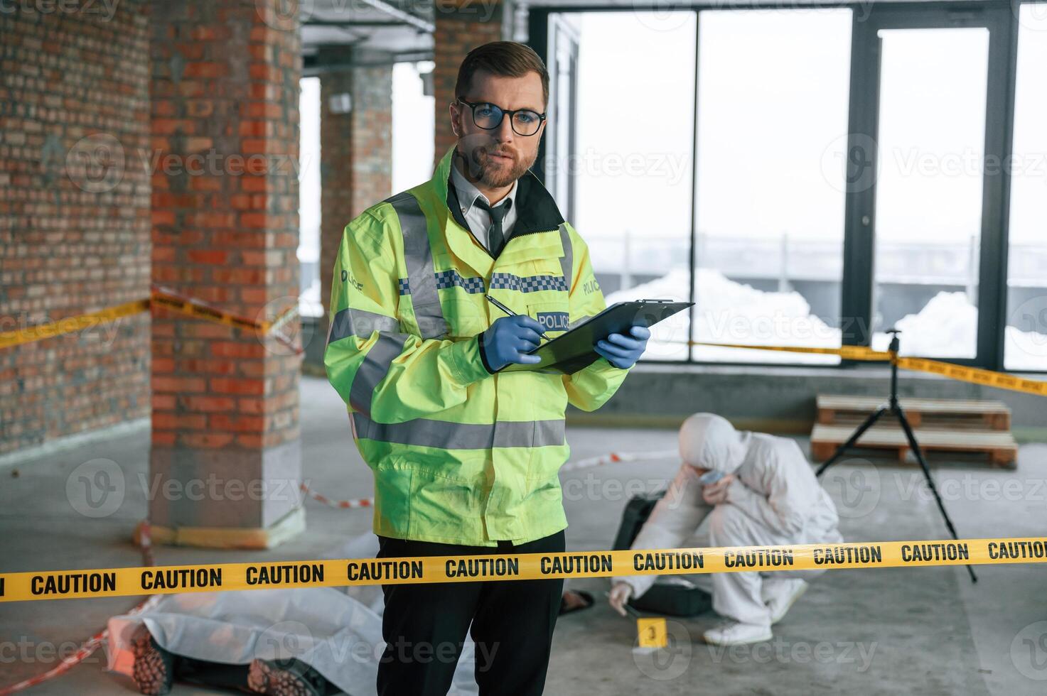 Man writing information into notepad. Detectives are collecting evidence in a crime scene near dead body photo
