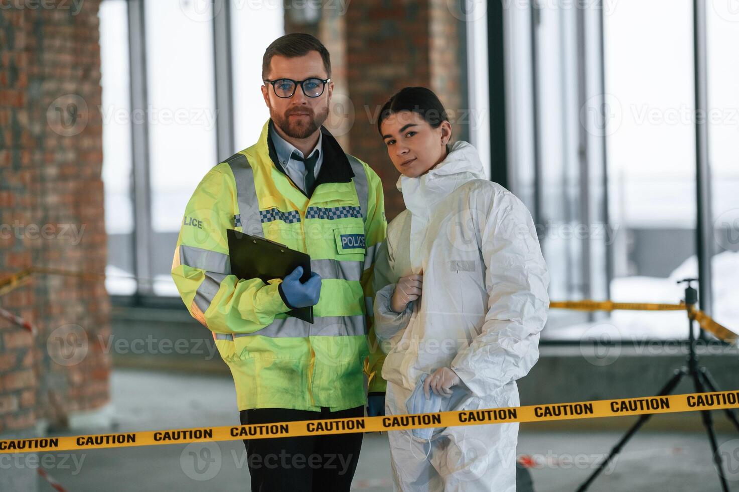 Standing and posing. Two detectives are collecting evidence in a crime scene. Forensic specialists are making expertise photo