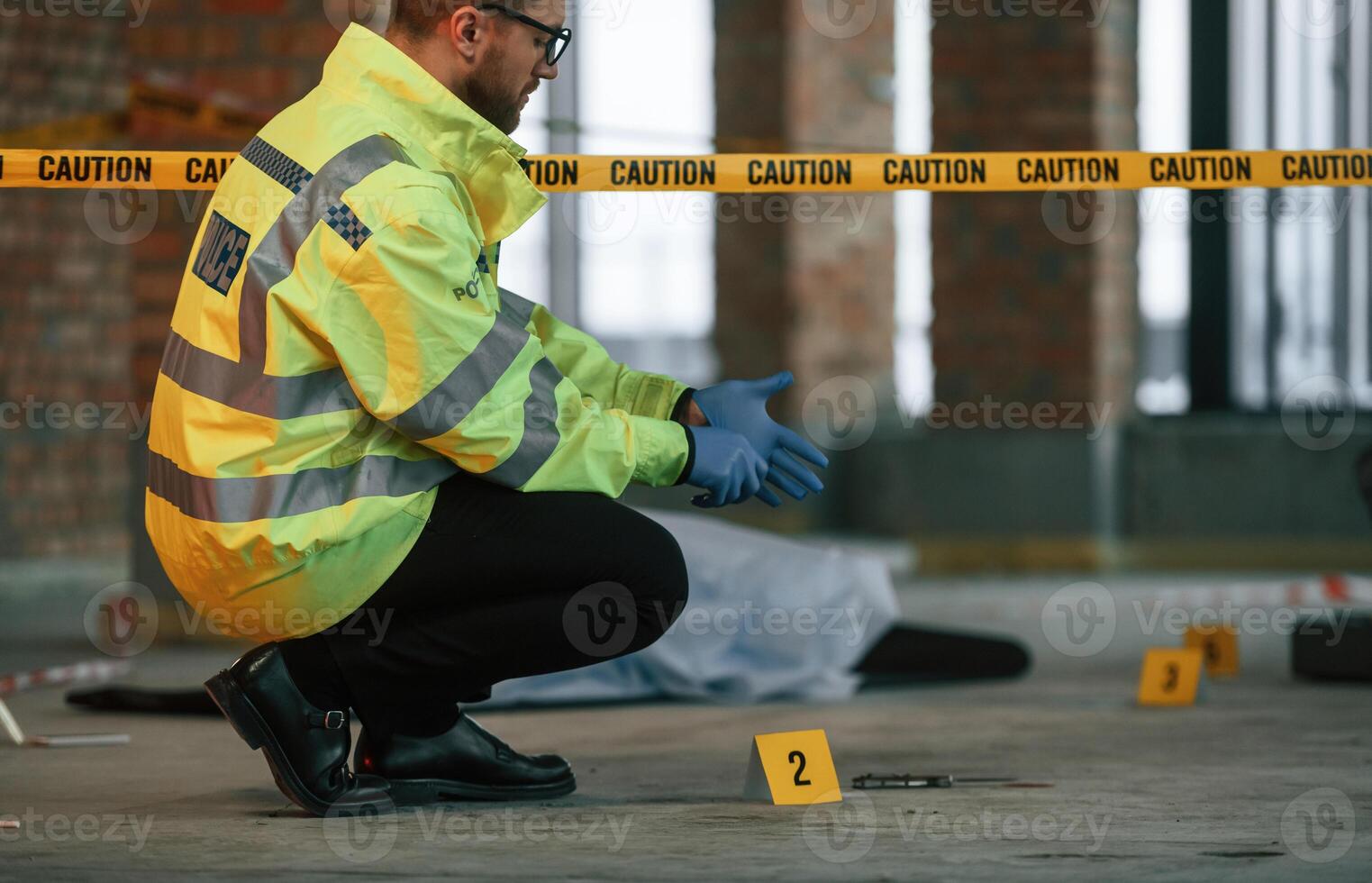 Wearing gloves. Male detective i,s collecting, evidence in a crime scene near dead body on the construction site photo