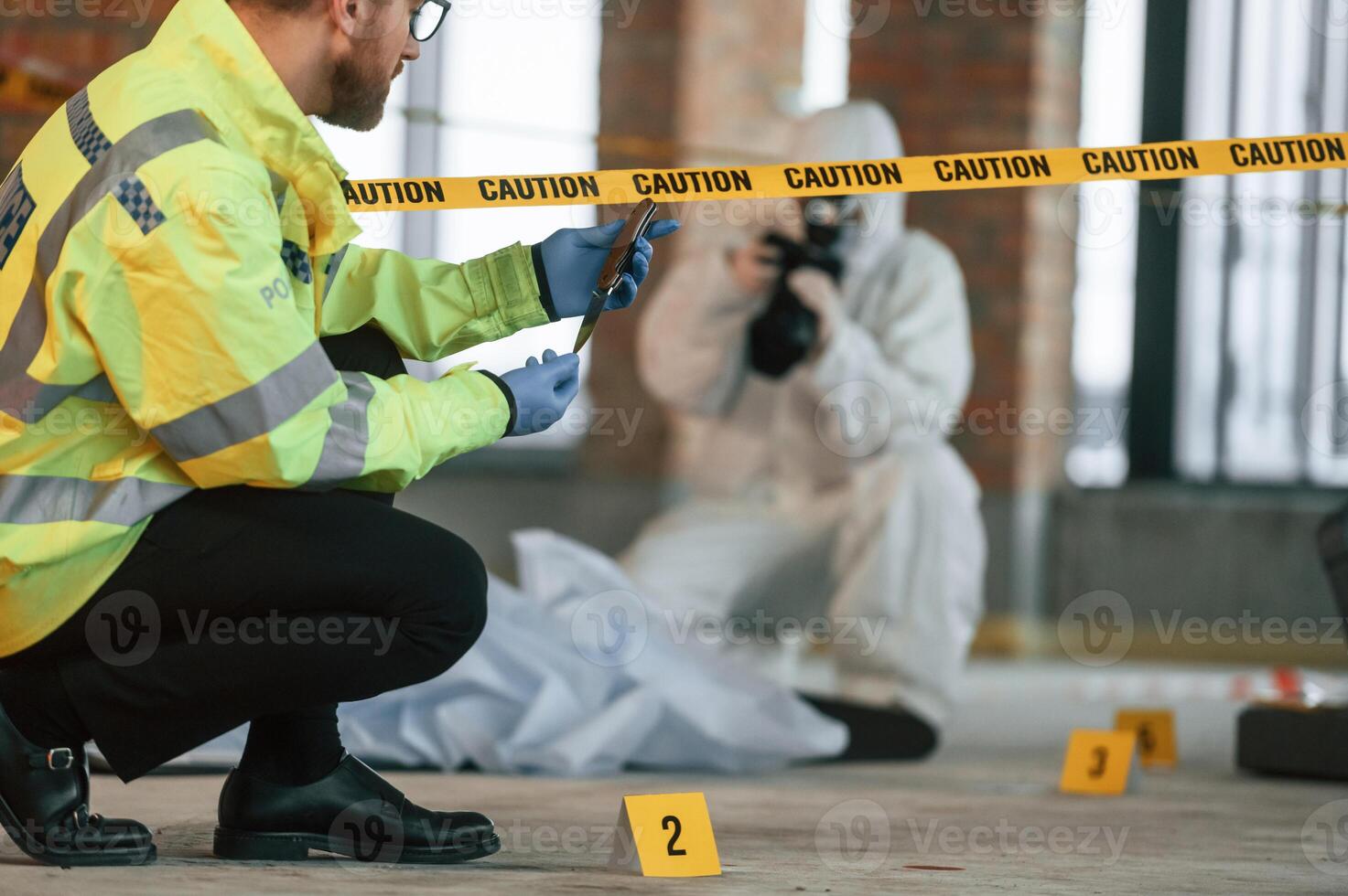 Woman is, using camera, making photos. Detectives are collecting evidence in a crime scene near dead body photo