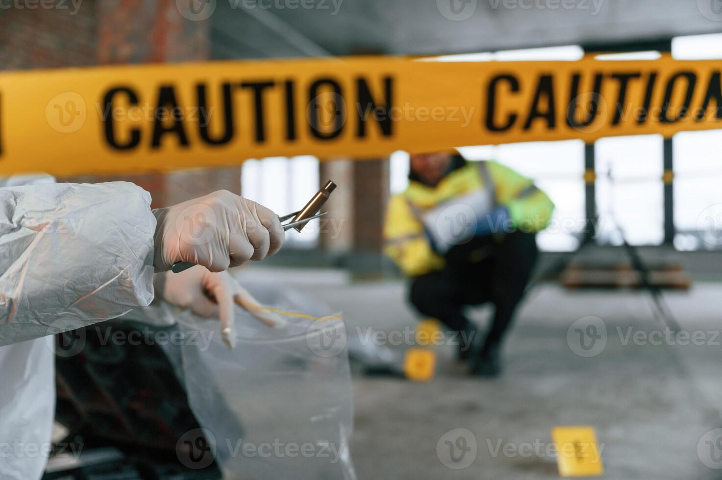 Woman holds the sleeve from the cartridge and puts it in the bag. Detectives are collecting evidence in a crime scene near dead body photo