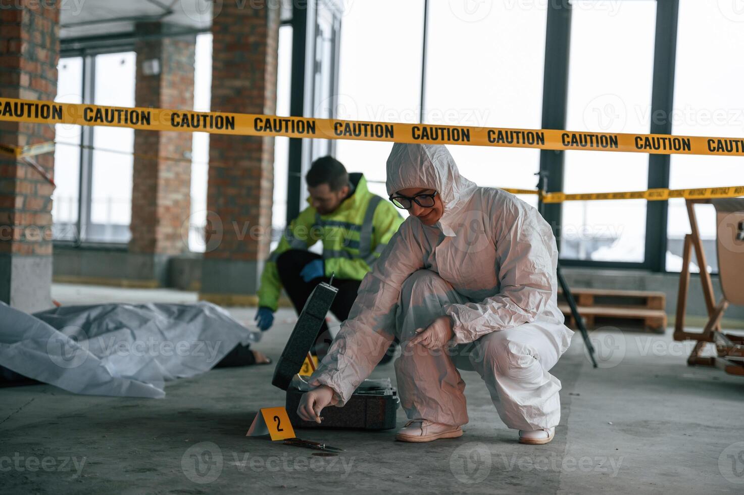 Knive ,and blood is on the ground. Detectives are collecting evidence in a crime scene near dead body photo